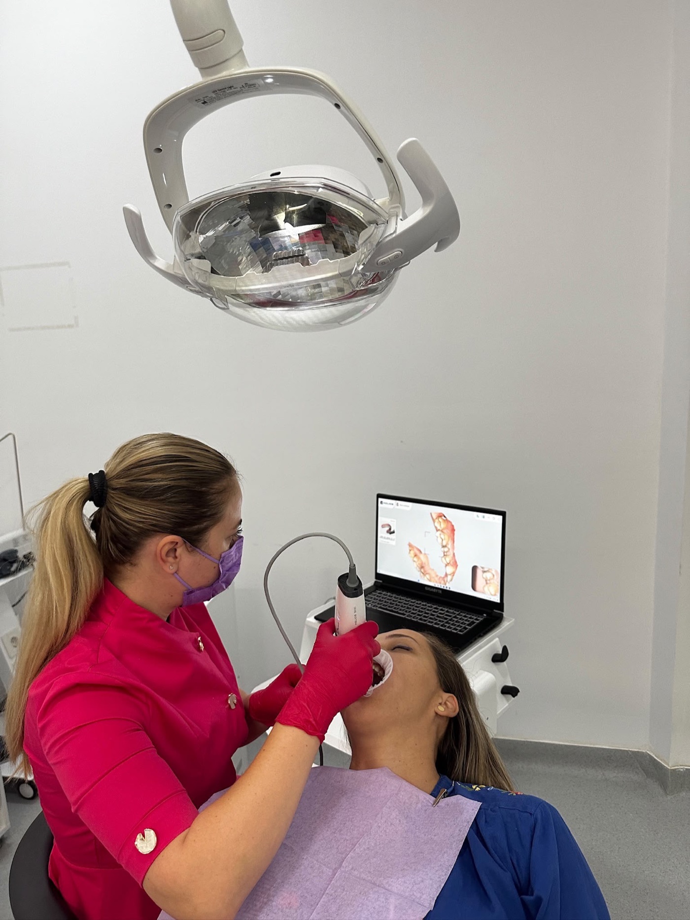 Dr. Laura Darawsha scanează dinții unei paciente cu scannerul intraoral